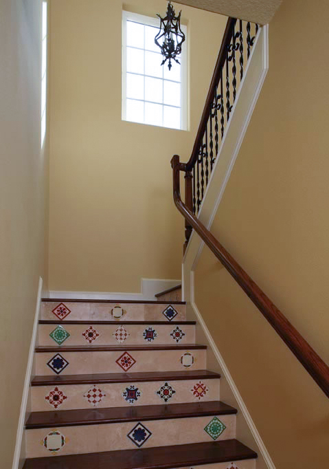 The Mediterranean flavor of this home is aptly displayed by a medley of mosaic tiles accenting the staircase, and the wood and wrought iron railing system.