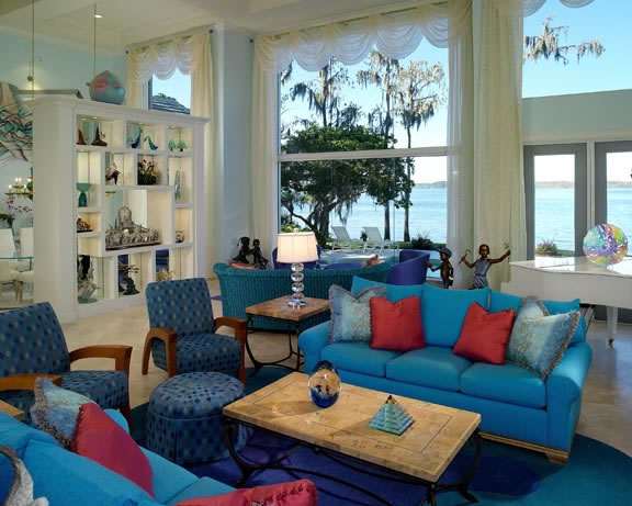 In the generously sized great room, bold blue furnishings set against a soft color palette of aqua and white highlight the owner's love of their art collection. Always in touch with the lake, a custom designed, free-standing art display by Busby Cabinets separates the living room from the dining room without sacrificing the lake view.